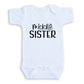 A white baby onesie with the text "middle SISTER" printed on it.