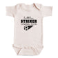 A baby onesie with the text "little STRIKER COMING SOON" printed on it, along with a soccer ball graphic.