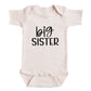 A baby onesie with the text "big sister" printed on it.