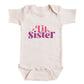 A white baby onesie with the text "Lil Sister" printed on it in a stylized font.