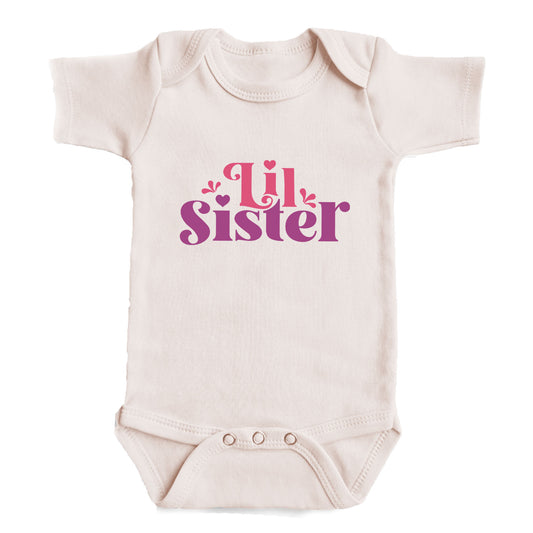 A white baby onesie with the text "Lil Sister" printed on it in a stylized font.