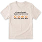 A beige t-shirt with the text "Grandma's PUMPKIN PATCH" printed on it, along with three orange pumpkins.