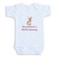 A white baby onesie with a printed image of a rabbit and the text "Grandma's little bunny" printed on it.
