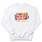 A white sweatshirt with a graphic design featuring the word "Auntie" surrounded by colorful flowers and leaves.