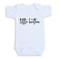 A white baby onesie with the text "title brother" printed on it.