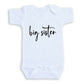 A white baby onesie with the text "big sister" printed on it.