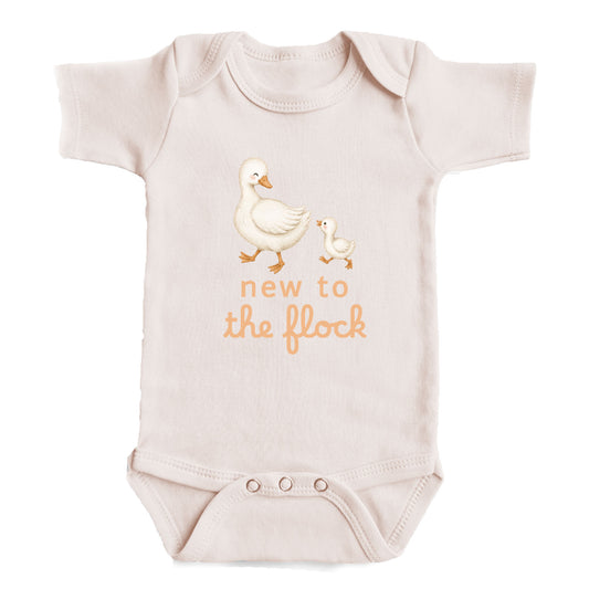 A baby onesie with a cartoon image of a mother duck and her duckling, along with the text "new to the flock" printed on it.