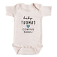 A baby onesie with the text "baby Thomas coming soon" printed on it.