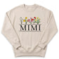 A beige sweatshirt with a graphic design featuring colorful flowers and the word "Mimi" printed on it.