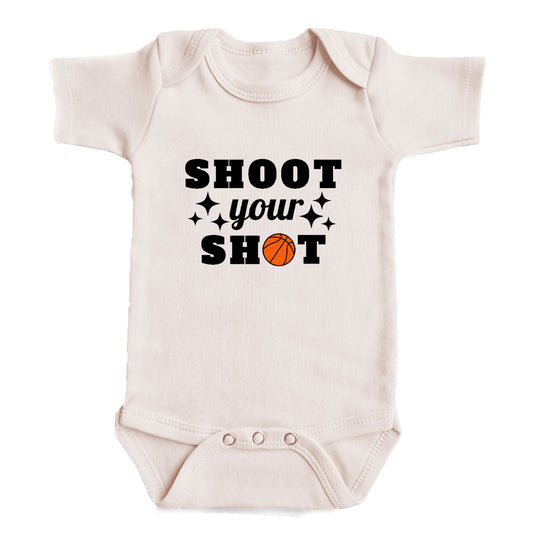 A white baby onesie with the text "SHOOT YOUR SHOT" printed on it.