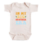 A baby onesie with the text "IN MY BIG BROTHER ERA" printed on it.