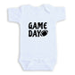A white baby onesie with the text "GAME DAY" printed on it.