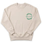 A beige sweatshirt with a green wreath design on the left side and the word "blessed" written in cursive script.